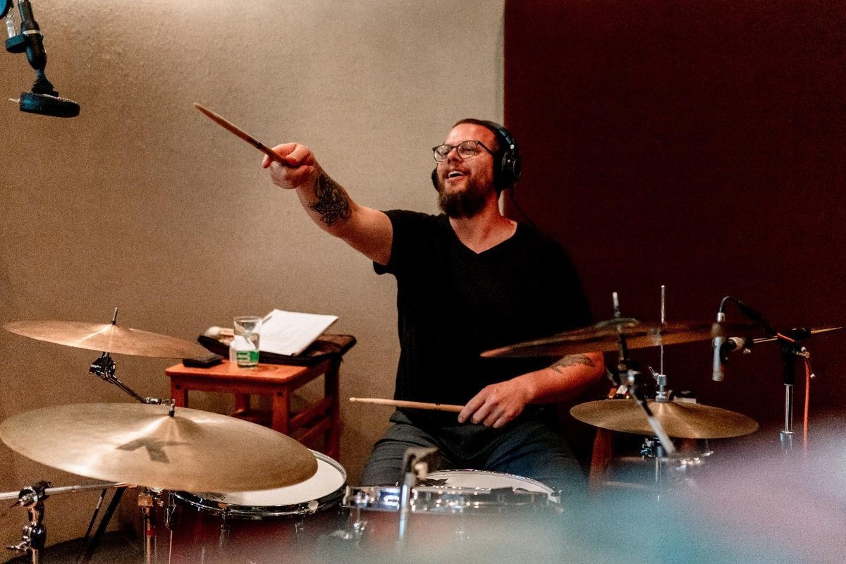 Sean Truskowski laughing behind his drum kit, sticks in hand