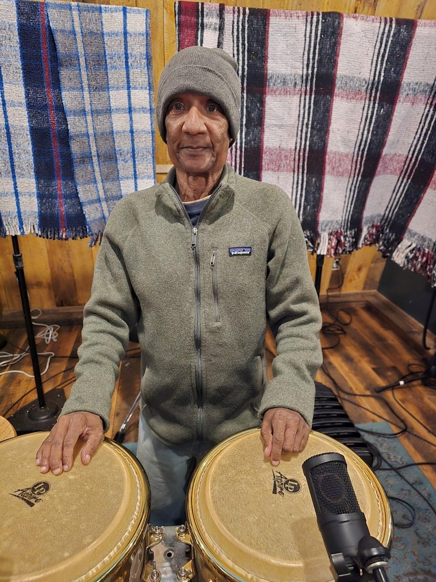 Enrique More standing at his congas in a barn studio