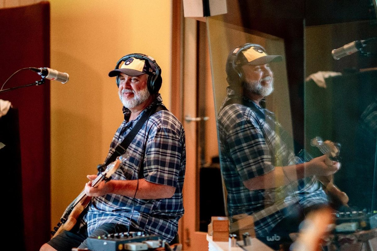 Eric Guido Lemon playing bass in the studio wearing a ball cap and headphones